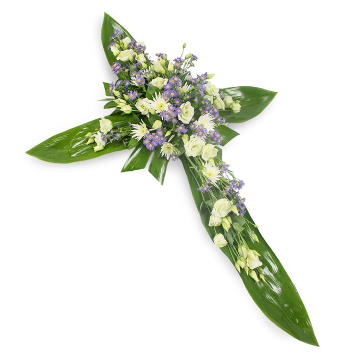 A quietly luminous cross of flowers and glossy green leaves, photographed from a slight overhead perspective against a plain white field so every shape and hue reads with clarity. The arms and central spine are formed by broad, tropical-style leaves with a waxy sheen and visible veins, their rich green establishing a serene, almost protective frame. Resting atop that verdant base is a concentrated flourish of blossoms: soft, ivory-to-cream lisianthus open in layered ruffles, each petal folding like a small, gentle wave; interspersed white chrysanthemums bring a compact, comforting texture; and the faintly violet sprays of limonium or delicate asters scatter like dusted lavender across the surface, adding depth and a whisper of cool colour. Fine green filler foliage is threaded through the clusters, giving a meadow-soft edge to the crisp geometry of the cross. The light is even and forgiving, lending a pale radiance to the whites and revealing the subtle tonal differences between ivory and pure white, while the lavender accents read as a calm, hopeful note. Crafted for funeral chapels, memorial services, or to stand at a graveside, this piece balances dignity with tenderness - firm structure softened by ephemeral blooms. For those in Rickmansworth seeking a floral symbol of faith and remembrance, the composition suggests both steadfast support and the gentle passing of seasonal life, making it an apt tribute at moments of mourning and reflection.
