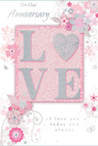 This anniversary card presents a gentle celebration of enduring romance, its design reminiscent of a pastel-toned bouquet one might order for delivery across Rickmansworth. The central focus is the word LOVE, set in softly raised letters that gleam with a fine coating of pale glitter. The letter O is transformed into a shimmering silver heart, slightly more textured than the other letters, so it would feel distinct if traced with a fingertip. The palette throughout the card is built from soft pastel pinks, delicate mauves, and cool silvery greys, all layered over a blush background that feels almost like watercolour washed across textured paper. Surrounding the central word, a constellation of delicate blooms unfurls, their petals lightly shaded and outlined in flowing lines that give an impression of movement, as though a breeze from the Aquadrome lakes were passing gently through a garden. The flowers are stylised rather than botanically precise, but their curves and layered petals echo romantic roses and garden blossoms a local florist would weave into an anniversary bouquet. Slender vines, curled tendrils, and fine swirls weave between the flowers, interspersed with tiny butterflies and scattered petals that add a playful, whimsical note. Hints of silver foil at the edges of some flowers and leaves reflect the light like dew on morning blooms. The sentiments On Our Anniversary and I love you today and always appear in a graceful, handwritten-style script, understated yet heartfelt, perfectly in tune with the card's softly intimate mood. It feels like a keepsake designed to mark a shared journey with tenderness in a Rickmansworth home.